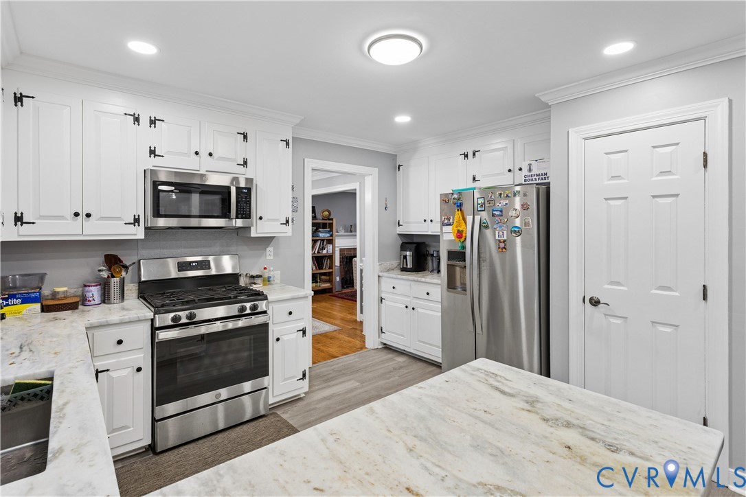 Kitchen featuring white cabinetry with exposed hinges, stone-surfaced countertops, stainless steel appliances, recessed lighting, and wood-finish flooring
