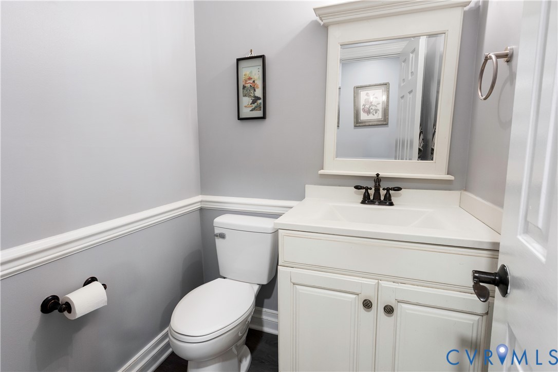 Powder room featuring a white vanity with an integrated basin, a framed wall mirror, a widespread faucet in a dark finish, and chair rail molding