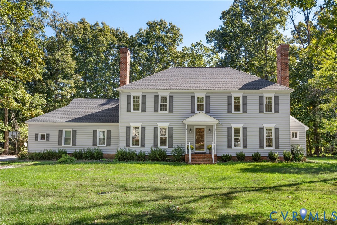 Traditional exterior featuring horizontal siding, dual brick chimneys, symmetrical multi-pane windows with shutters, and an elevated entry portico