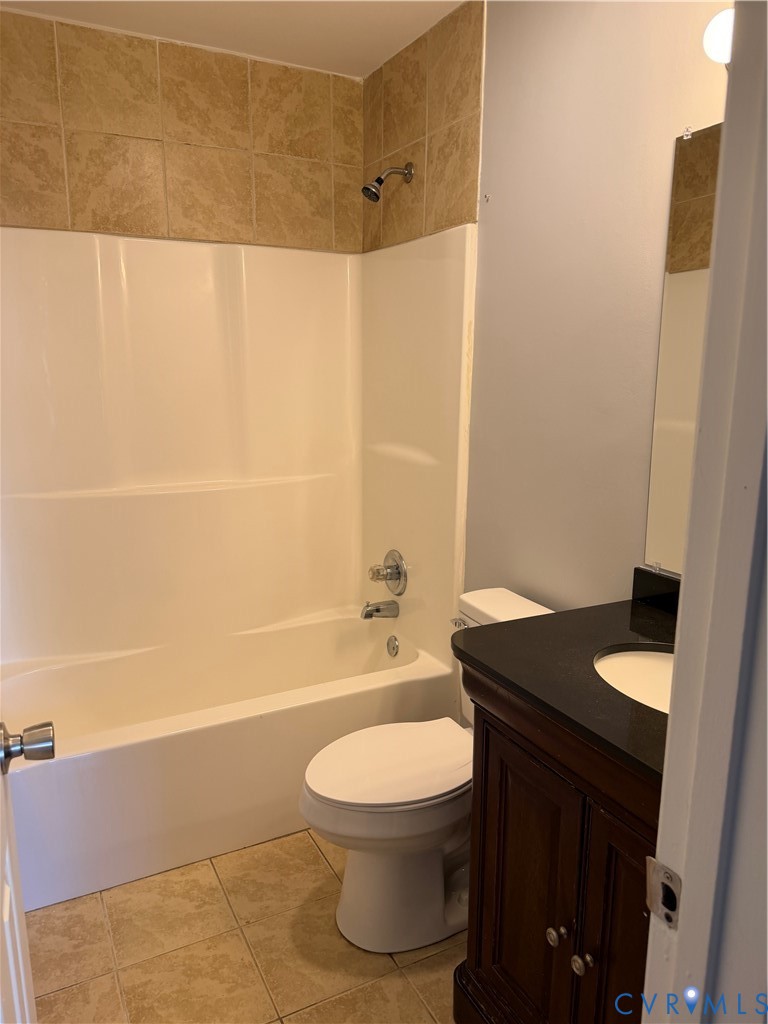 Bathroom featuring a vanity with a dark countertop and integrated sink, a combination shower and tub, and tile flooring