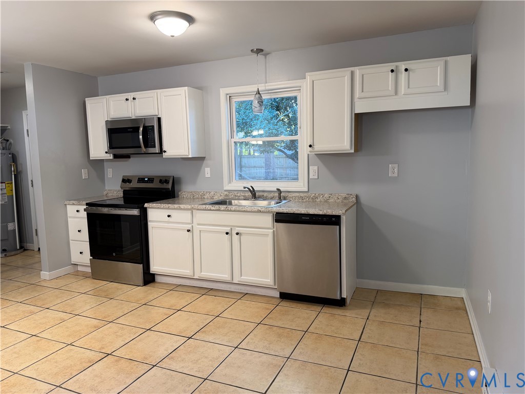 Kitchen featuring white cabinetry, stone-finish countertops, stainless steel appliances, and tile flooring