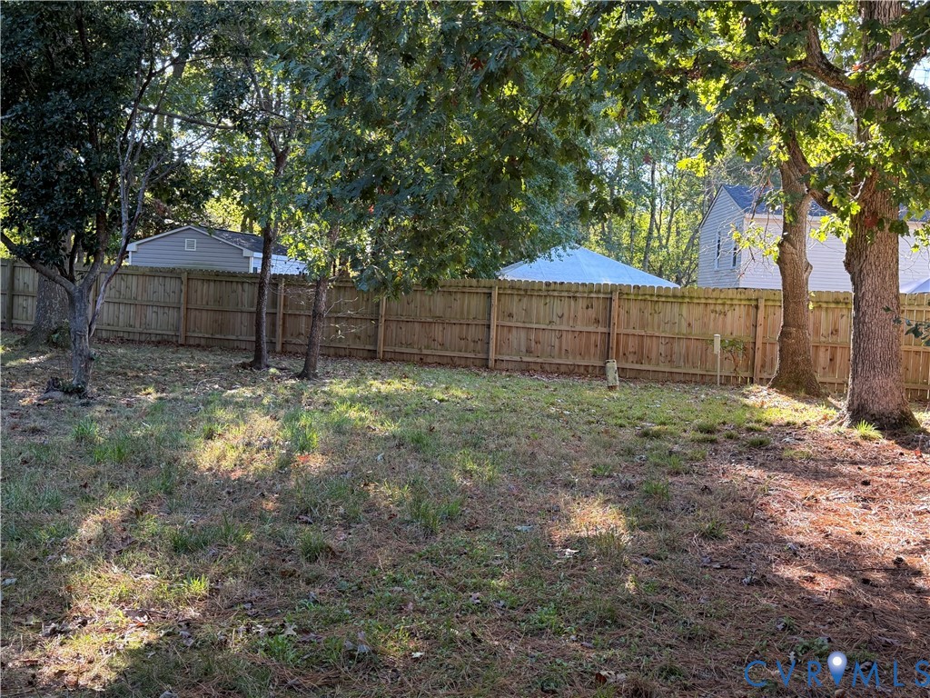 Expansive backyard featuring a wood privacy fence and mature canopy trees