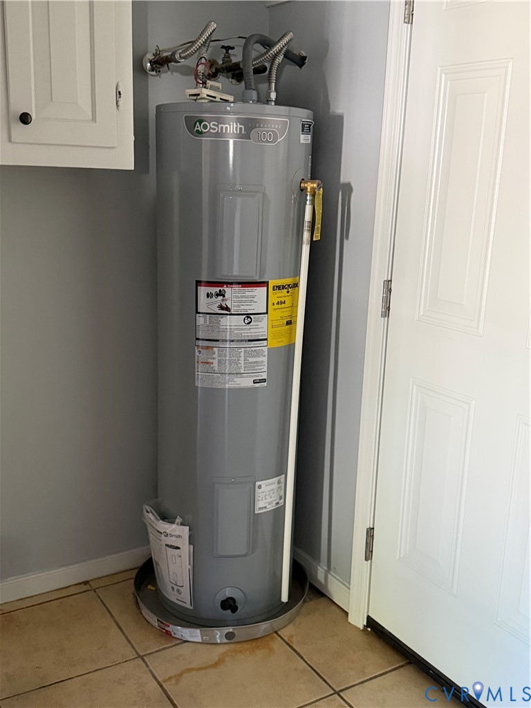 AO Smith water heater featuring a cylindrical metal tank, pressure relief valve, and a protective drain pan, positioned on ceramic tile flooring