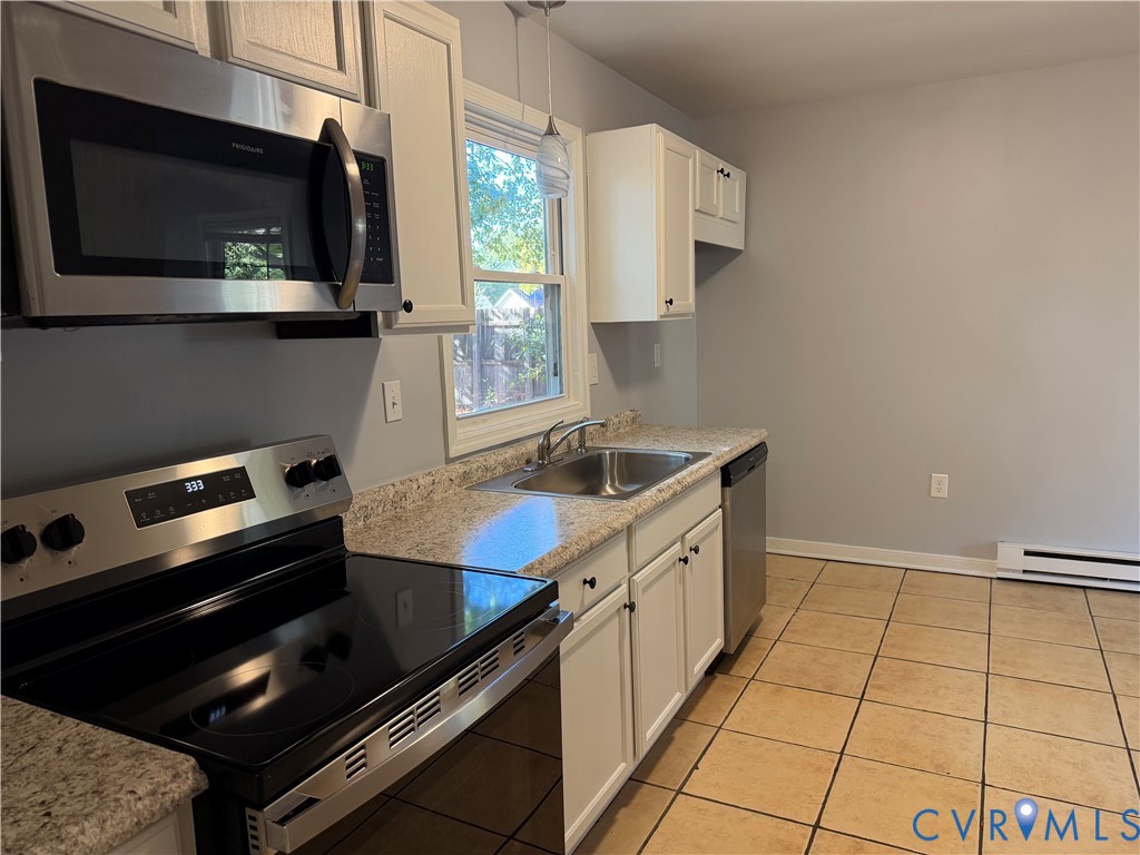 Kitchen featuring white cabinetry, stone-finish countertops, stainless steel appliances, a double-basin sink, and tile flooring
