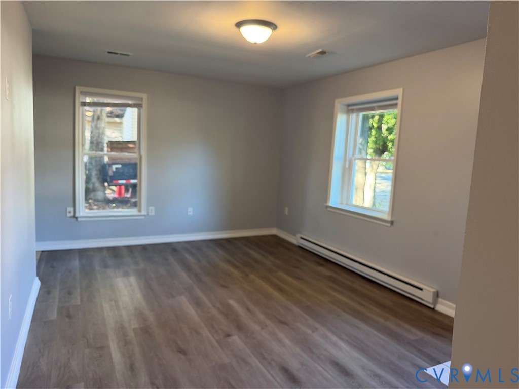 Neutral interior room featuring wood-finish flooring, dual windows, and a ceiling-mounted light fixture