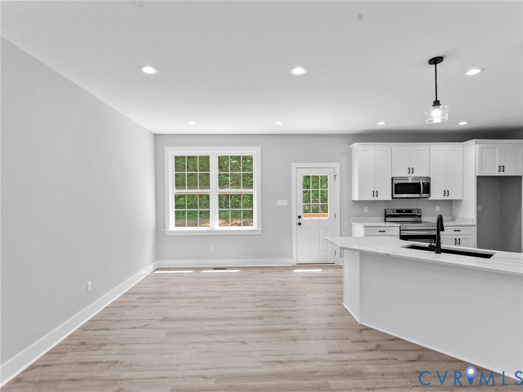 Kitchen featuring white cabinetry, wood-finish flooring, recessed lighting, a kitchen island, and a glass-panel exterior door