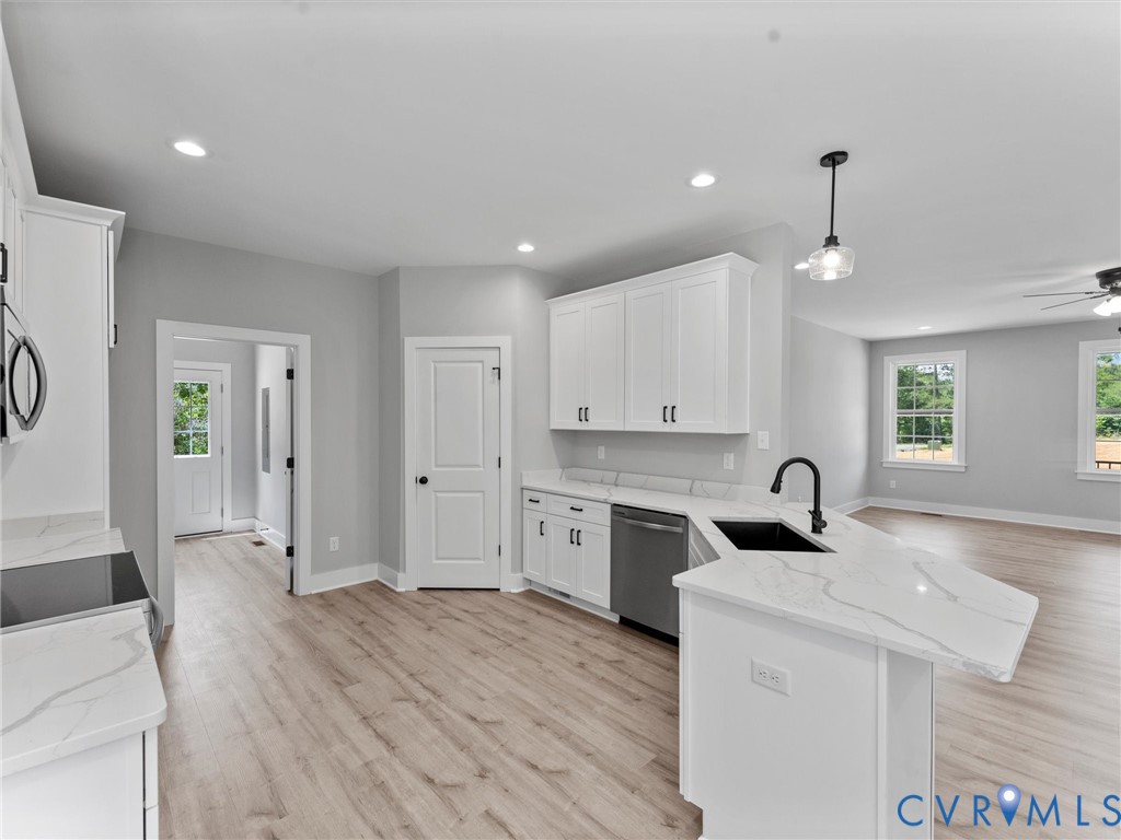 Kitchen featuring white shaker-style cabinetry, white countertops with grey veining, a matte black faucet with an undermount sink, recessed lighting, and wood-finish flooring