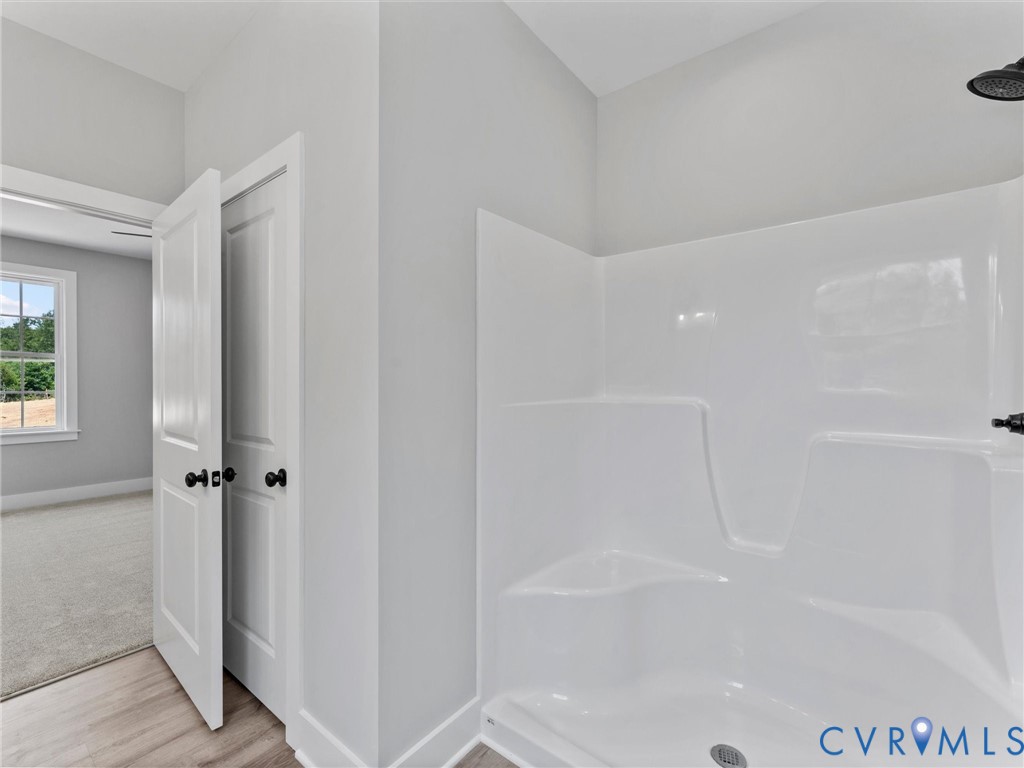 Molded acrylic shower surround with integrated seating, matte black shower fixture, and interior doors featuring matte black hardware