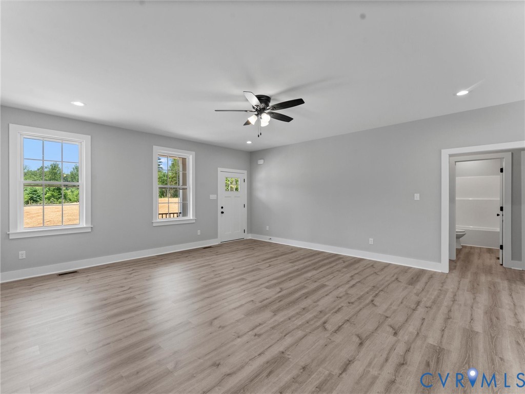 Interior space featuring wood-finish flooring, recessed lighting, a multi-blade ceiling fan with integrated light fixture, dual windows, and a glass-paneled exterior door
