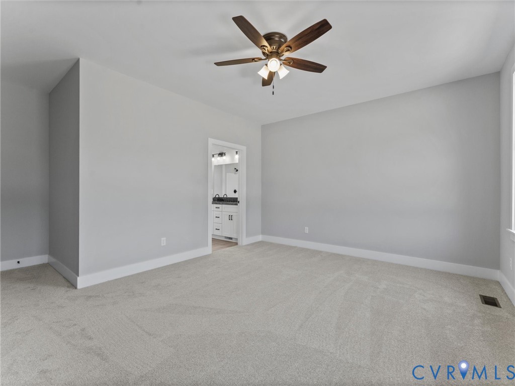 Neutral-toned carpeted flooring, multi-blade ceiling fan with integrated light fixture, and neutral wall paint