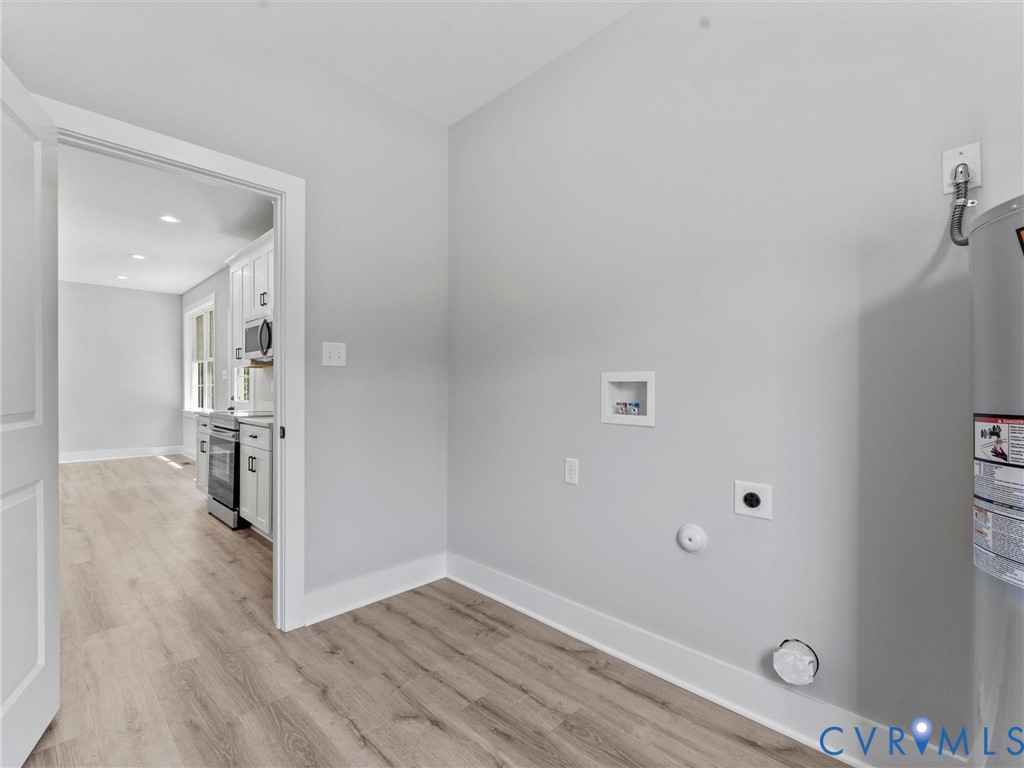 Utility area featuring wood-finish flooring, neutral wall tones, and dedicated washer and dryer hookups