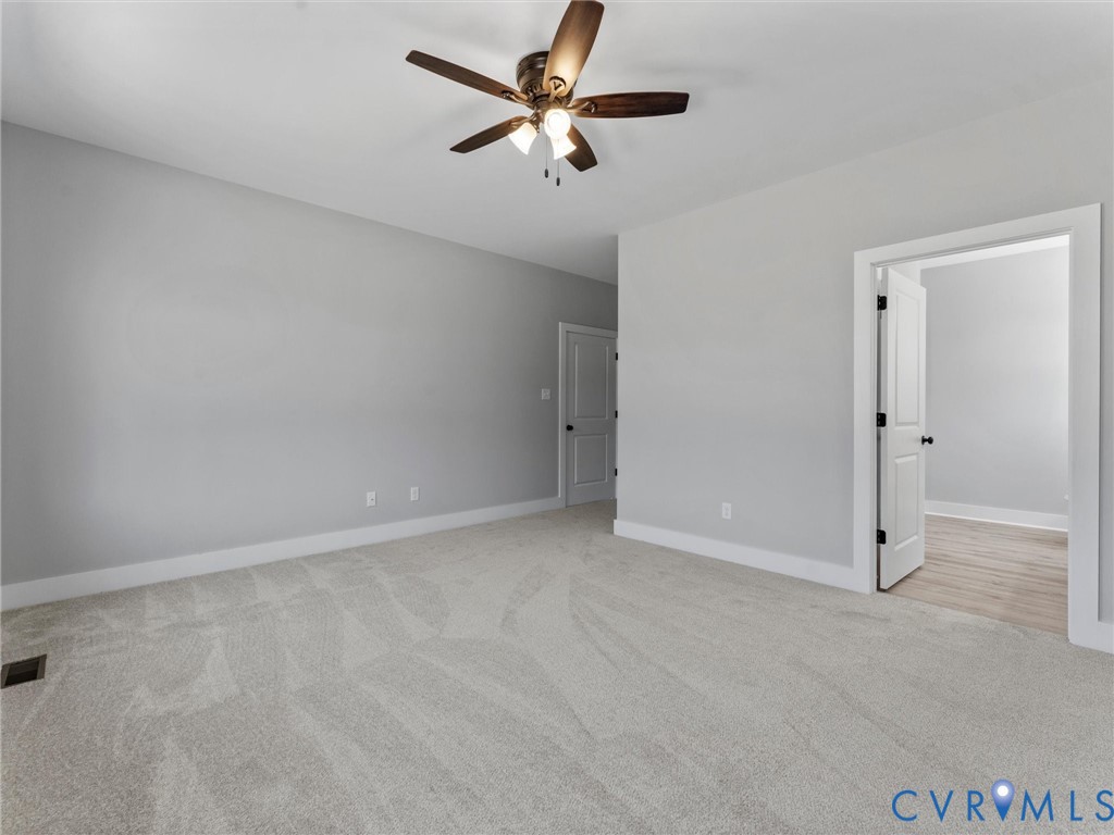 Neutral-toned wall paint, plush carpeting, ceiling fan with integrated lighting, and multi-panel interior doors