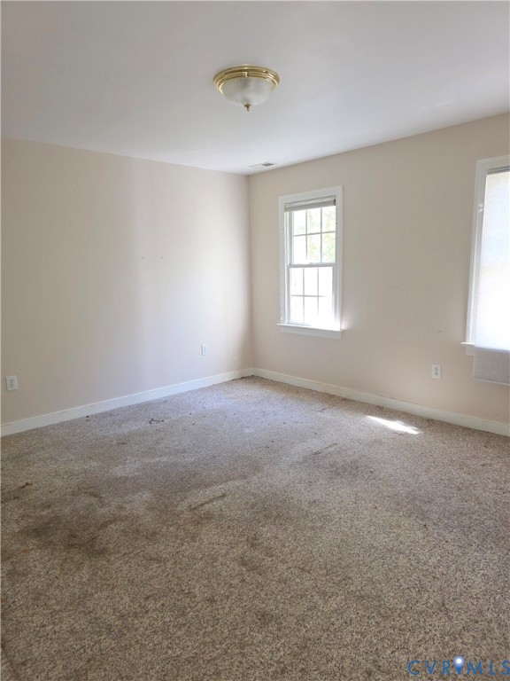 Neutral-toned walls, wall-to-wall carpeting, multiple double-hung windows, and a flush-mount ceiling light fixture