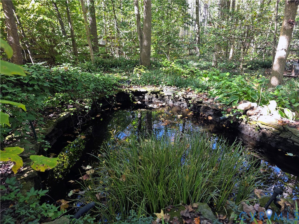 Natural stone-bordered pond set within a wooded landscape with established foliage