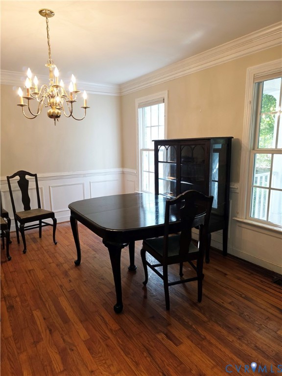 Wood-finish flooring, wainscoting, crown molding, multi-pane windows, and a multi-arm chandelier