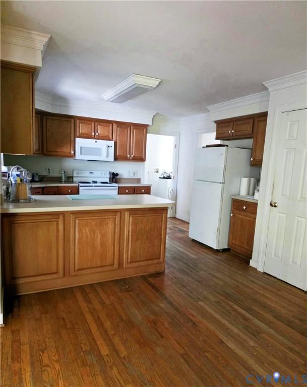 Kitchen featuring wood cabinetry, wood-finish flooring, a kitchen island, crown molding, and white appliances