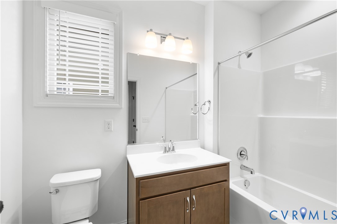 Bathroom with a wood-finish vanity, white countertop, and integrated sink