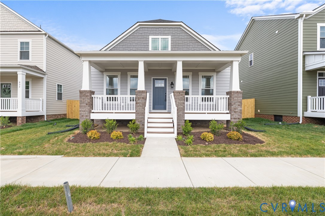 Craftsman-style home featuring a covered front porch with white railings and columns, stone accents, and a dark blue entry door