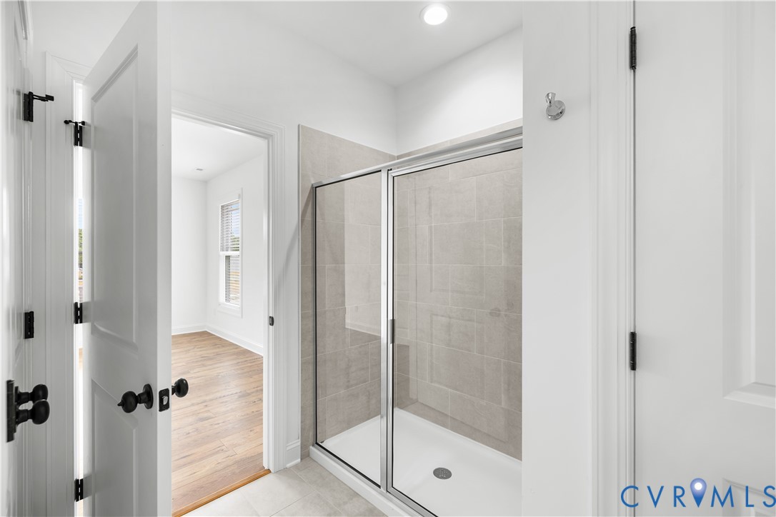 Shower enclosure with framed glass door, light grey tile surround, and white shower pan