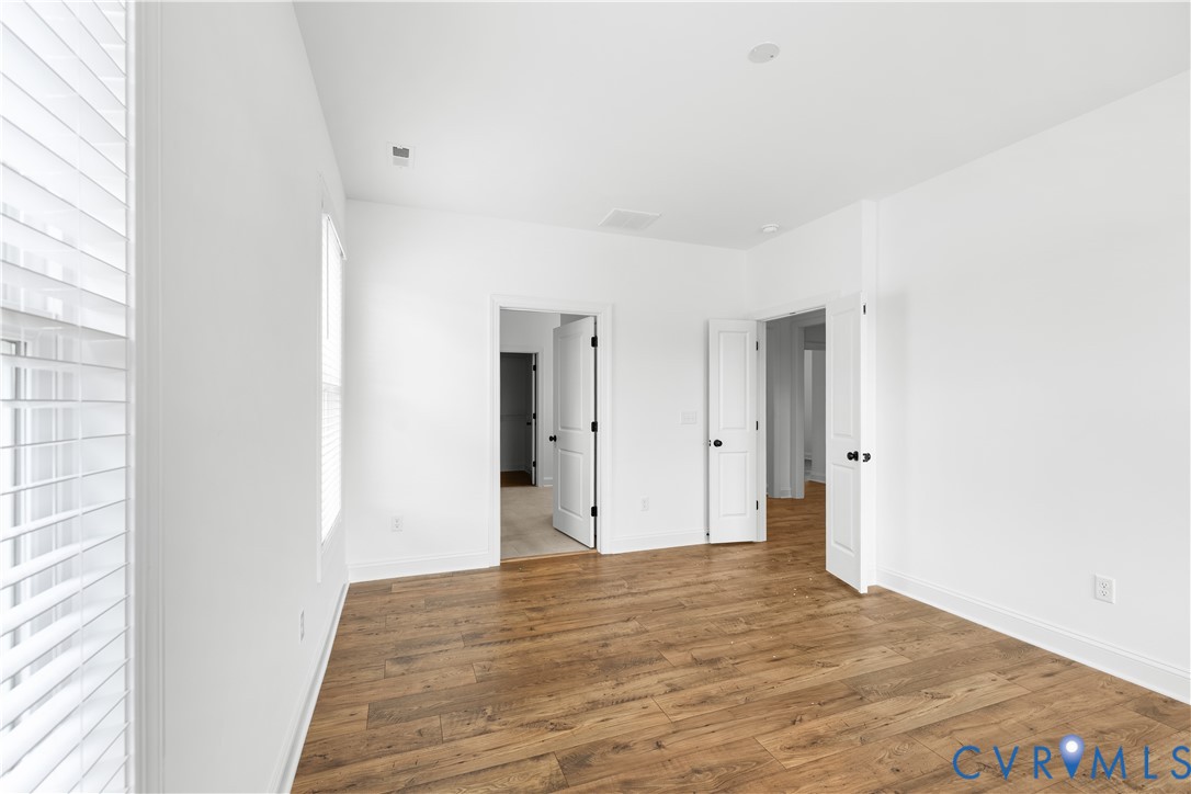 Bright room featuring wood-finish flooring, white walls, and white trim