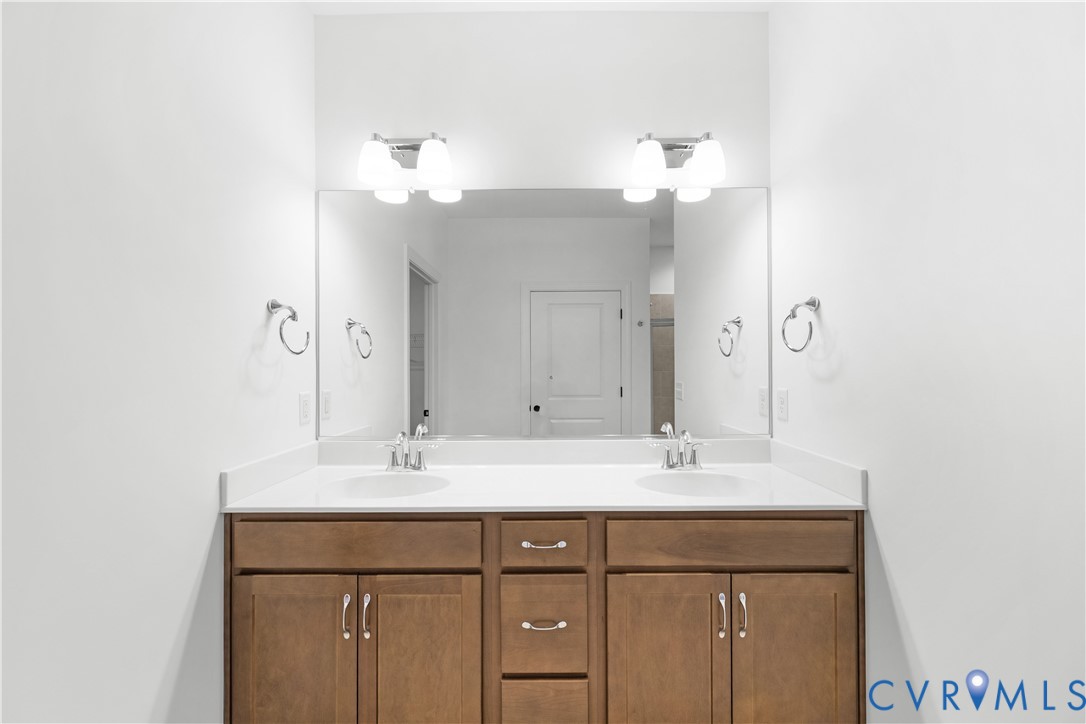 Double vanity with wood-finish cabinetry, white countertop, and dual undermount sinks