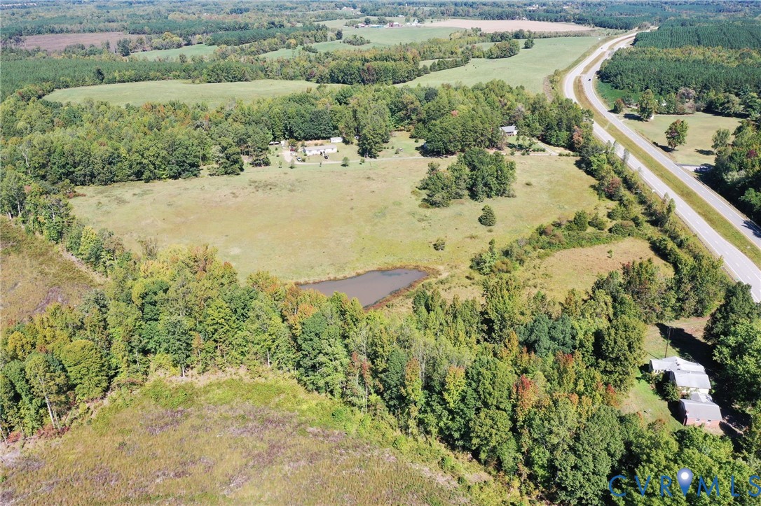 Aerial view of expansive acreage featuring open pasture, mature woodland, and a private pond Aerial view of expansive acreage featuring open pasture, mature woodland, and a private pond