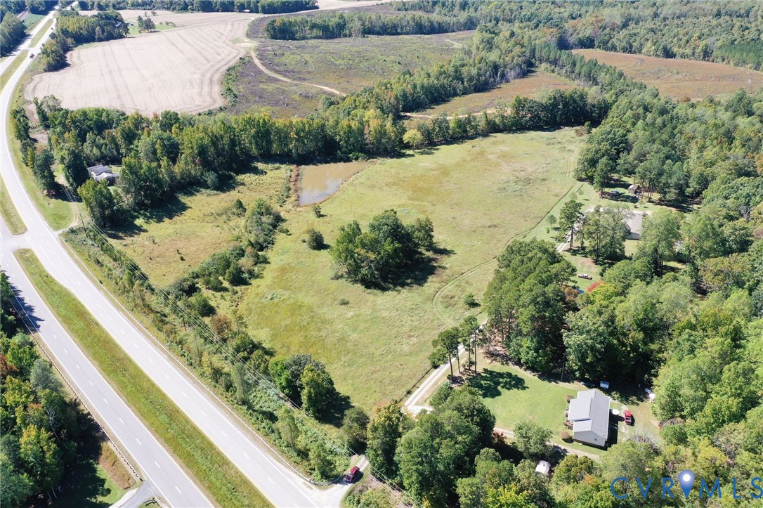 Aerial perspective of expansive acreage featuring open pasture land, a natural pond, and mature tree clusters Aerial perspective of expansive acreage featuring open pasture land, a natural pond, and mature tree clusters