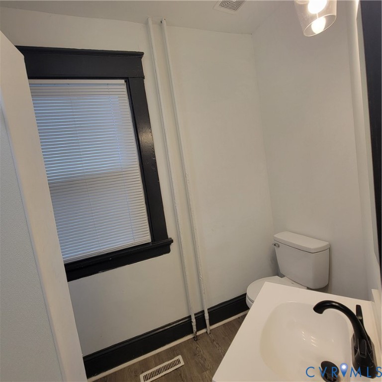 Restroom featuring a vanity with a white countertop, matte black faucet, wood-finish flooring, and high-contrast dark window trim