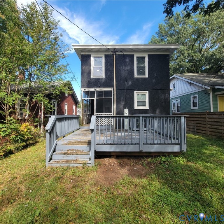 Exterior view featuring a textured black facade, a wooden deck with railing, a screened-in porch, and a backyard area