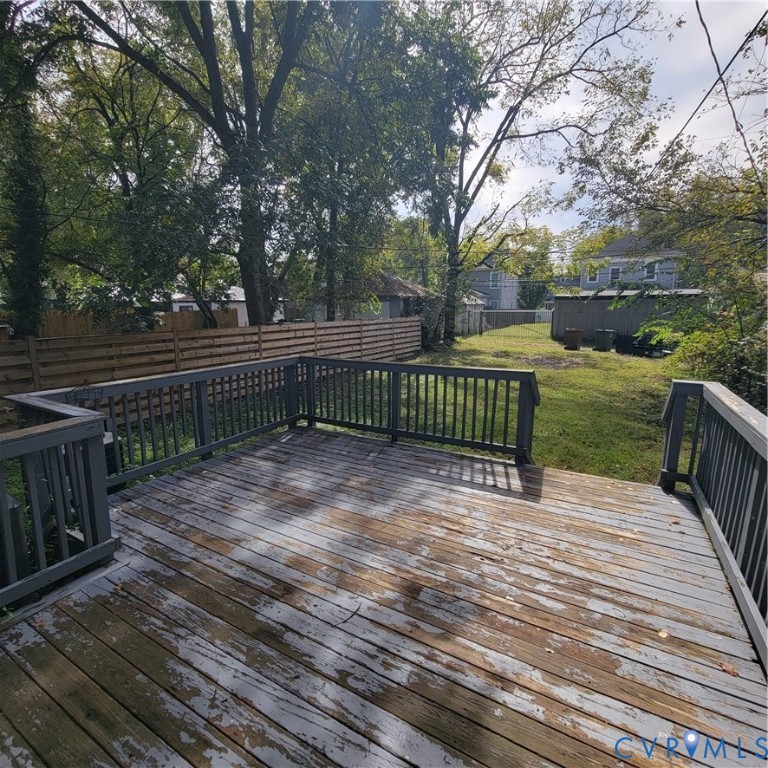 Elevated wood deck with perimeter railing and horizontal wood-slat privacy fencing