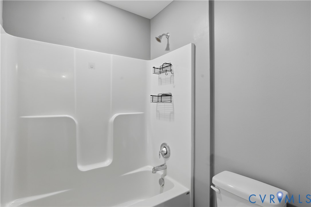 Jack and Jill Upstairs bathroom. Bathtub and shower combination featuring a seamless white surround, chrome-finished wall-mounted shower head, and matching metal faucet hardware