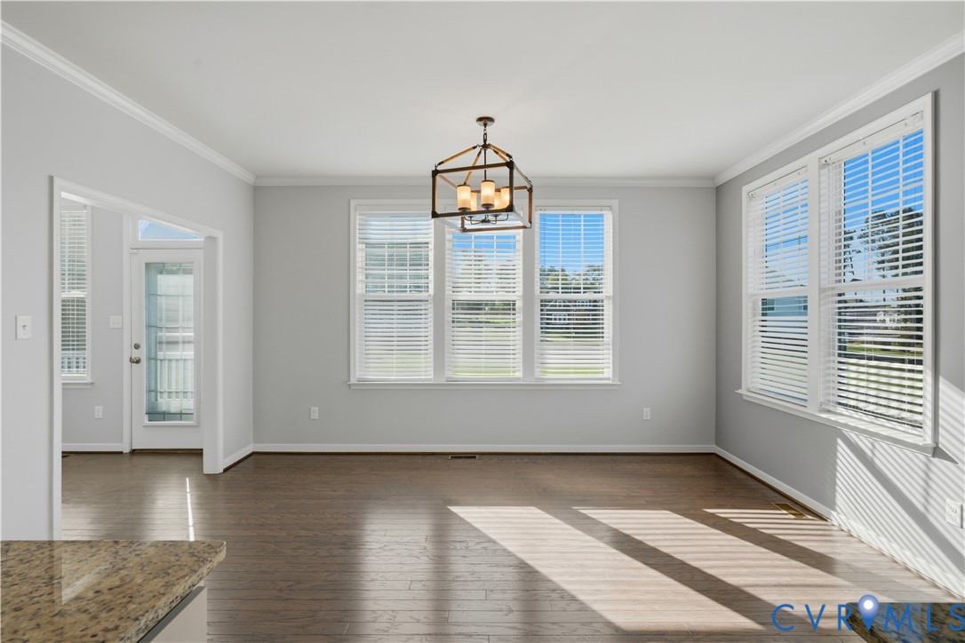 Open-concept room featuring wood-finish flooring, crown molding, a multi-light geometric chandelier, and large windows with horizontal blinds