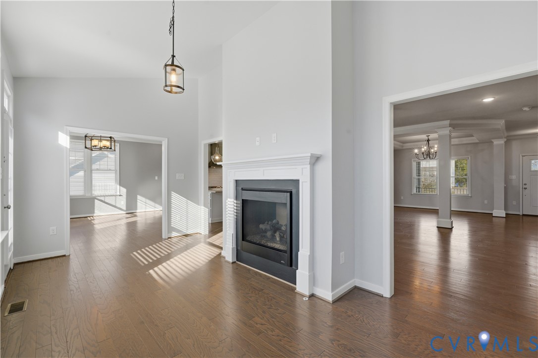 Vaulted ceilings, wood-finish flooring, and a fireplace featuring a detailed white mantel