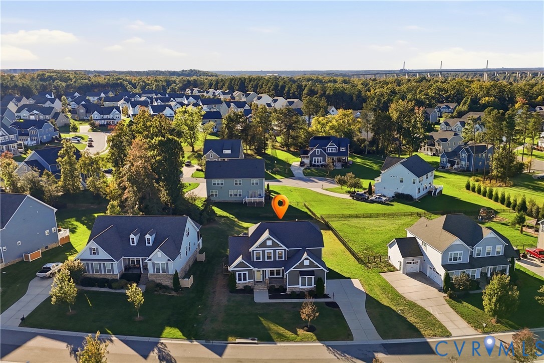 Aerial perspective of a detached residential property featuring a multi-gable roofline, a paved driveway, and a fenced rear yard