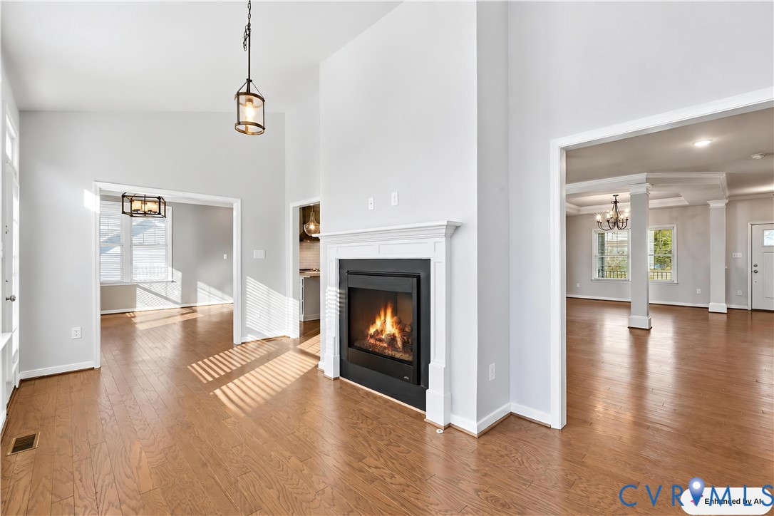 Fireplace with a classic white mantel surround, vaulted ceiling, wood-finish flooring, and pendant lighting