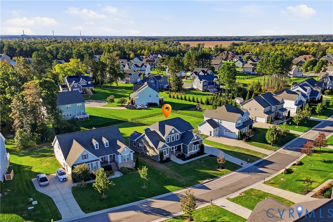 Aerial perspective of a multi-story residence featuring a dark shingle roof, a two-car attached garage, and a fenced rear yard