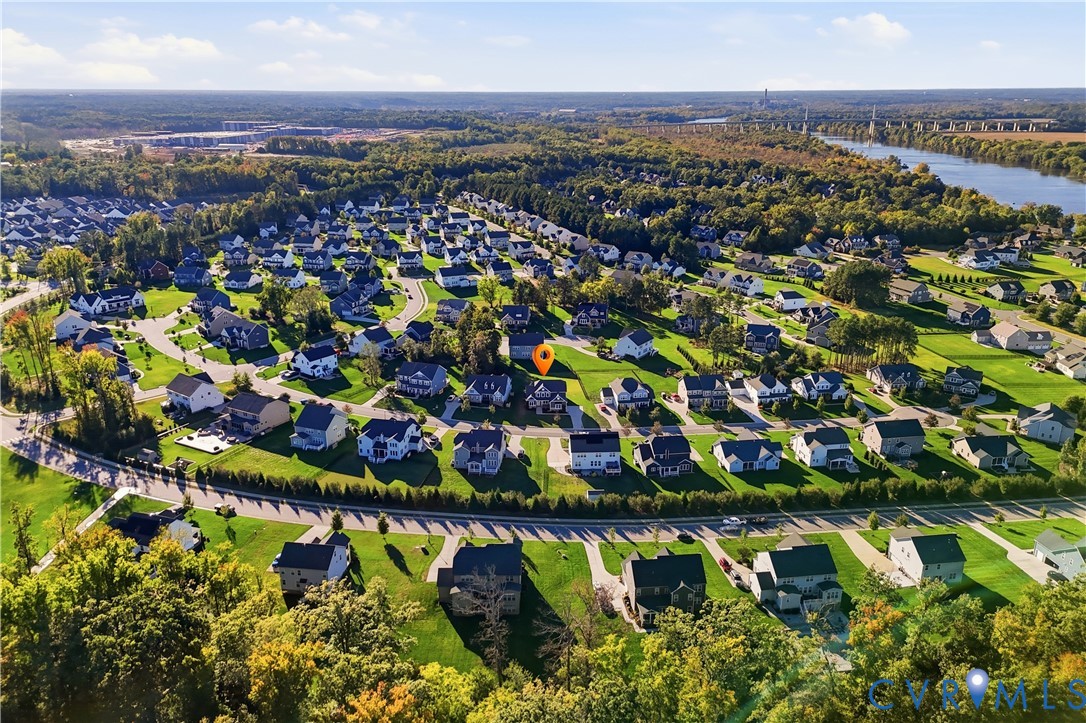 Aerial perspective featuring a residential community with paved streets, landscaped green spaces, and mature tree clusters