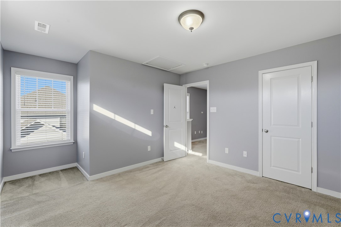 Bedroom #4 Neutral-toned interior space featuring neutral wall-to-wall carpeting, white two-panel interior doors, a multi-pane window with white trim, and a flush-mount ceiling light fixture