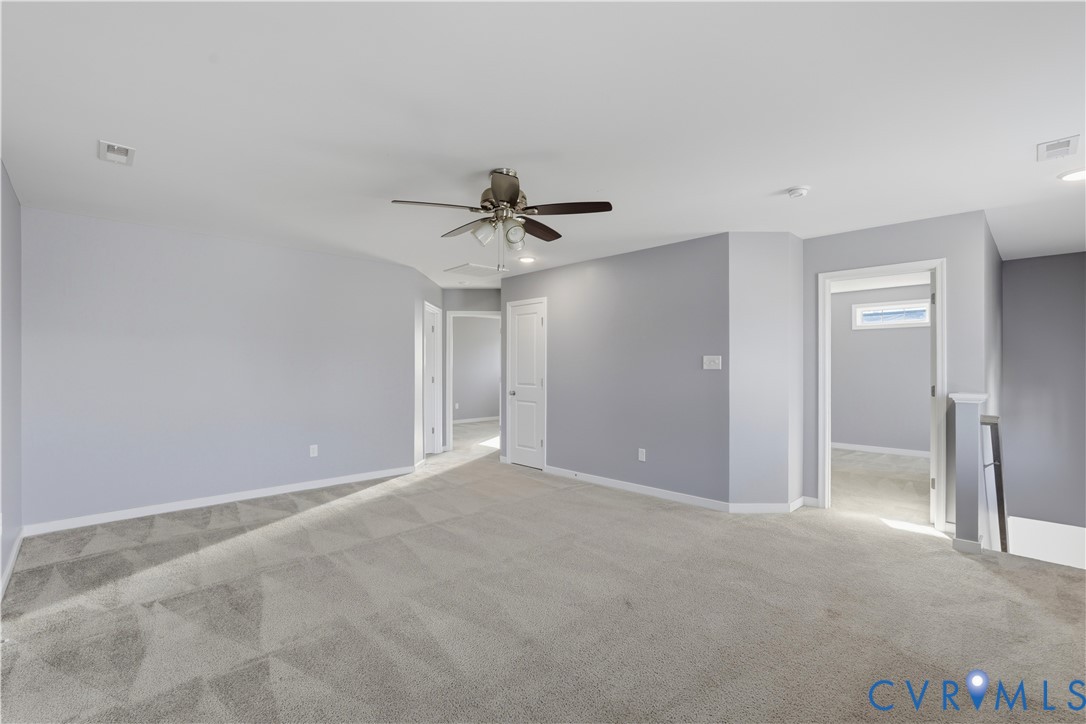 Interior space featuring neutral-toned carpeting, multi-panel doors, and a central ceiling fan with integrated lighting