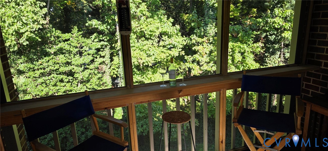 Screened-in porch featuring a wood railing, built-in ledge, and exposed brick wall Screened-in porch featuring a wood railing, built-in ledge, and exposed brick wall
