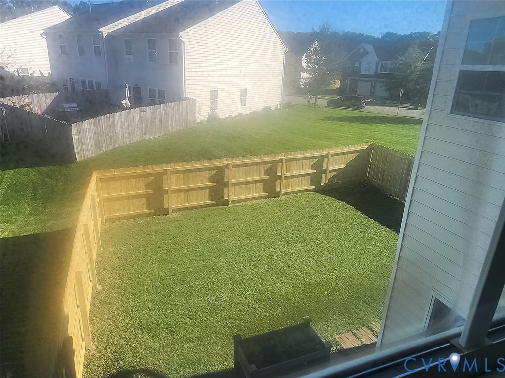 Rear yard featuring a grass lawn, wood-post fencing, and exterior siding