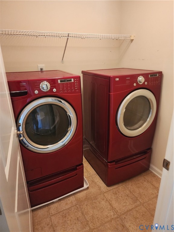 Laundry area featuring side-by-side high-capacity washer and dryer units with pedestal storage drawers and an overhead wire shelving rack