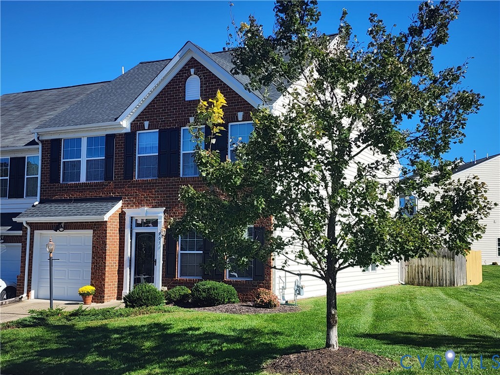 Multi-story brick facade featuring shuttered windows, a gabled roofline, single-car garage, and manicured lawn