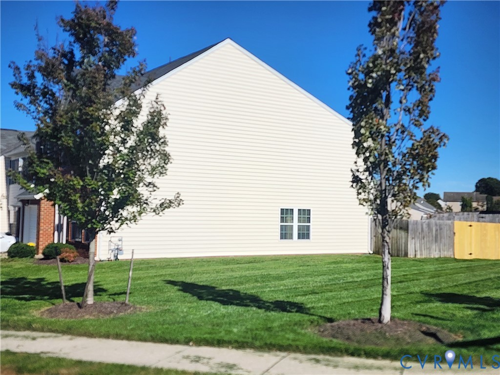 Light-toned siding exterior with double-pane windows, mature trees, and a grass lawn