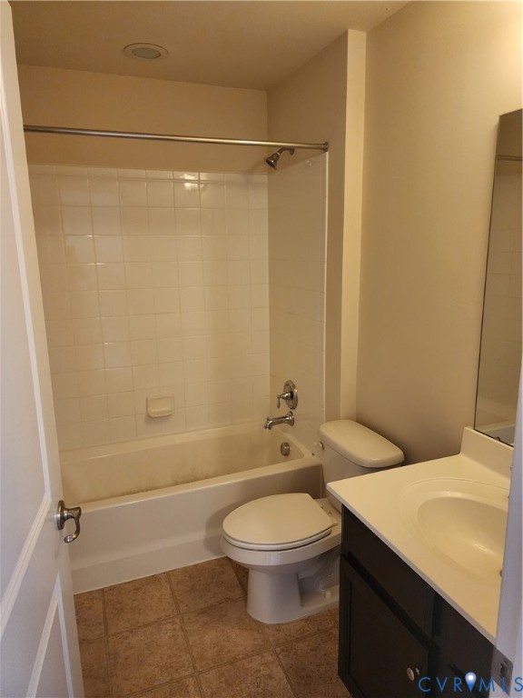 Bathroom featuring a dark-finish vanity with a white countertop, tub and shower combination with tile surround, and neutral floor tile