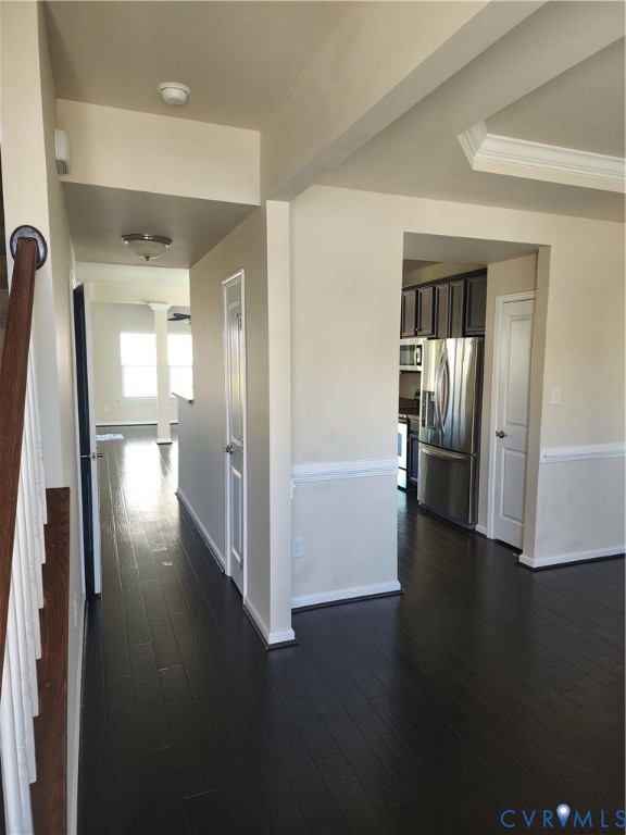 Dark-toned wood-finish flooring, tray ceiling with crown molding, chair rail trim, and stainless steel kitchen appliances