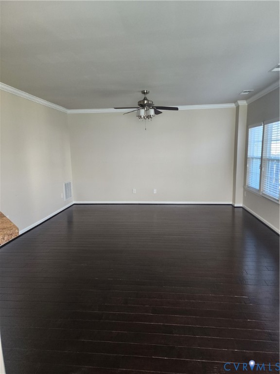 Dark wood-finish flooring, neutral wall tones, crown molding, and a central ceiling fan with integrated lighting