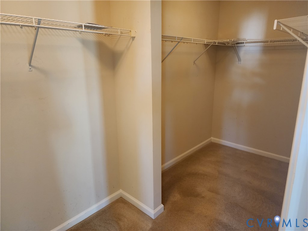 Walk-in storage space featuring neutral wall paint, wall-to-wall carpeting, and white wire shelving