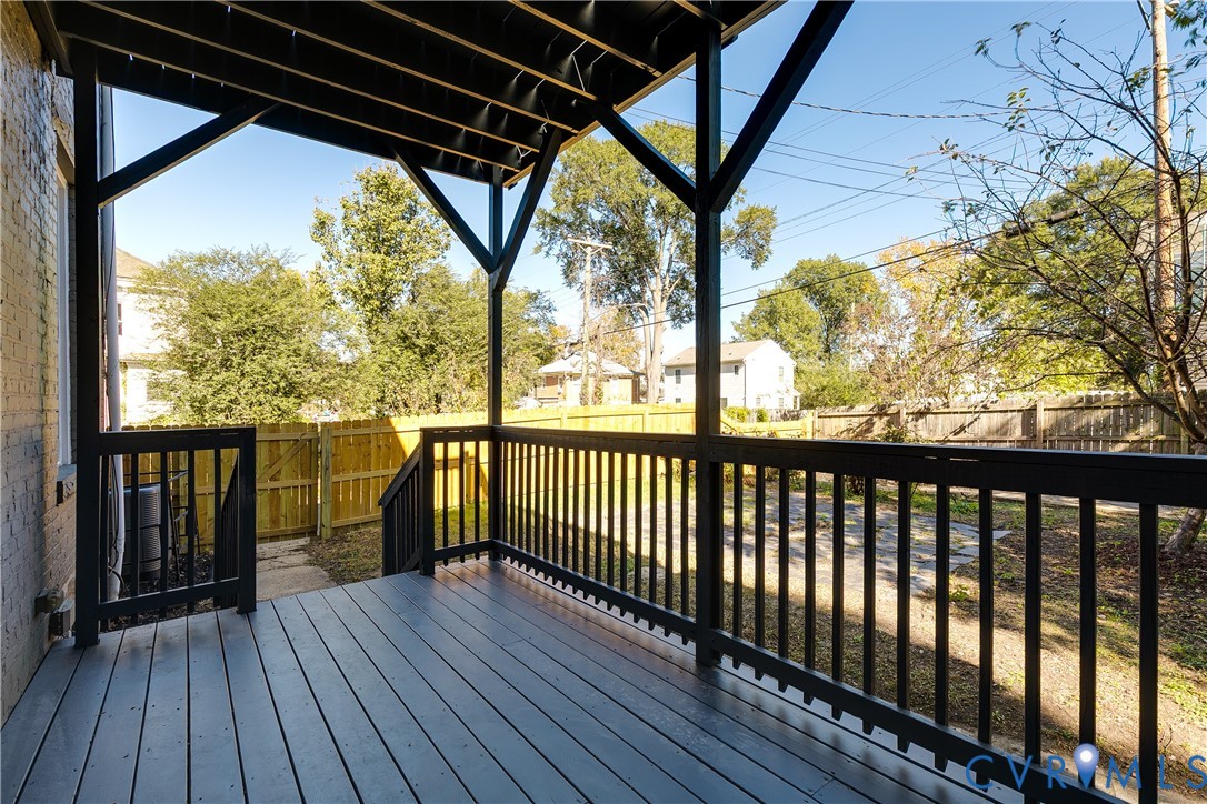 Covered wooden deck featuring dark-toned floorboards, black structural support beams, and matching black railings