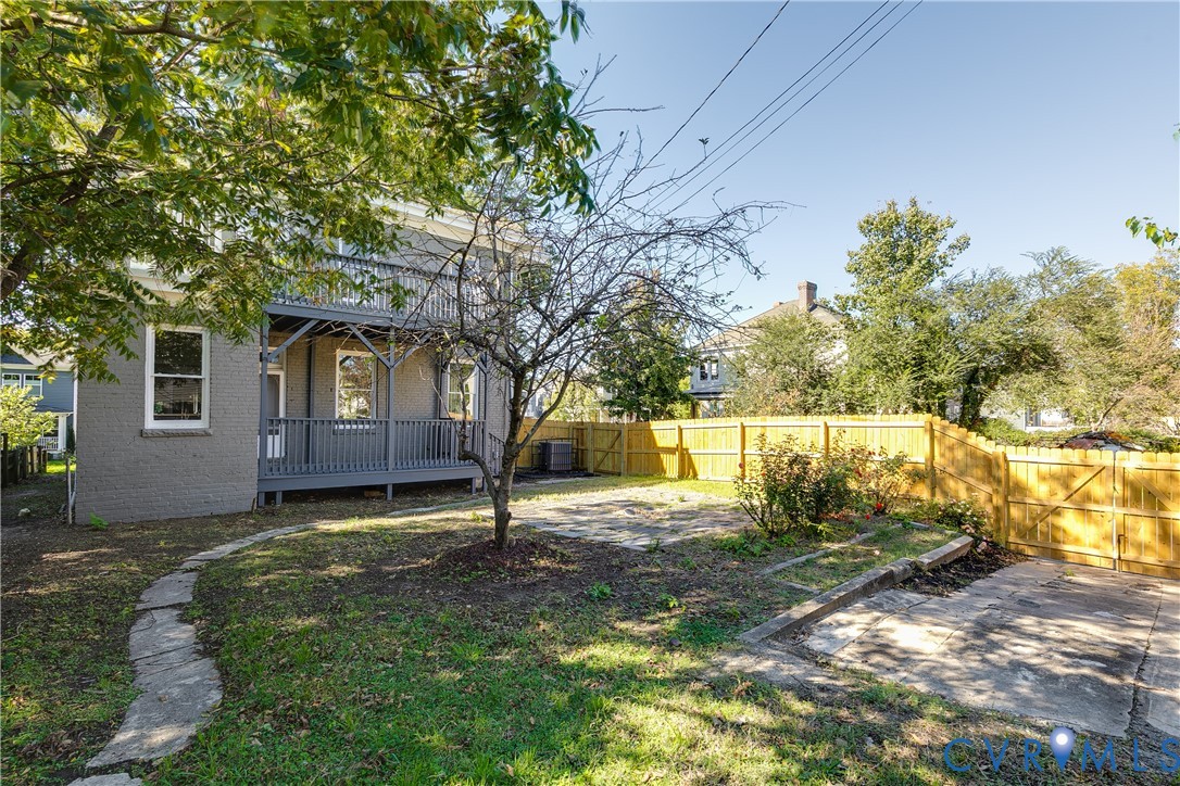 Exterior featuring a multi-level wooden deck, stone pathway, paved patio area, and privacy fencing